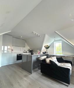 a living room with a black couch and a kitchen at The Penthouse Double Bedroom for Rent Free Parking in Epsom