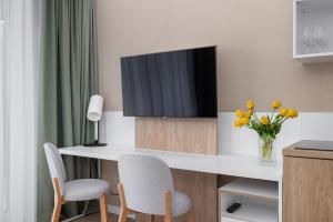 um quarto com uma secretária, uma televisão e flores em Bel Mare Green Leaf Studio with Balcony by Renters em Międzyzdroje