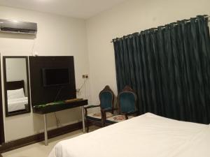 a bedroom with a bed and two chairs and a television at Hotel Inn Karachi in Karachi