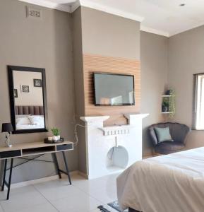 Schlafzimmer mit einem Bett, einem Schreibtisch und einem Spiegel in der Unterkunft Precious Estates Pearls in Zeerust