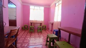 チェラプンジにあるPAMILYA HOMESTAYのピンクの壁、緑のテーブルと椅子が備わる客室です。