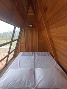 Ce lit se trouve dans une chambre en bois dotée d'une grande fenêtre. dans l'établissement Wawowow, à Tomohon