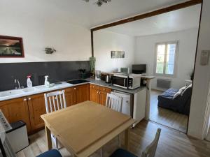 eine Küche und ein Wohnzimmer mit einem Tisch und einer Mikrowelle in der Unterkunft Le Chalet in Saint-Germain-en-Laye