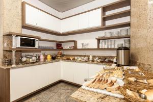a kitchen with white cabinets and a counter with bread at Letto Hotel Porto Alegre in Porto Alegre