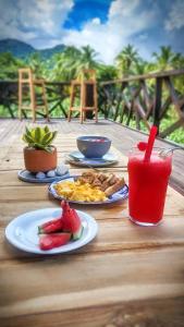 a wooden table with plates of food and a drink at Yaku Hostel in Playa Mendiguaca