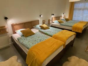 Dos camas en una habitación con mantas amarillas. en Vakantiewoning Het Wielje Maasland en Kinrooi