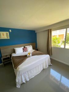 Un dormitorio con una cama grande con un osito de peluche. en Tarumã Búzios Hotel, en Búzios