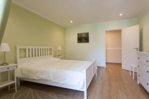 Schlafzimmer mit einem großen weißen Bett und Holzböden in der Unterkunft FLH Bairro Alto Artistic with View in Lissabon