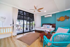 a bedroom with blue walls and a bed and chairs at Villapadu Bayu in Kuala Terengganu