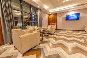a lobby with couches and a tv on a wall at Laten Suites Al Salim Plaza in Jeddah