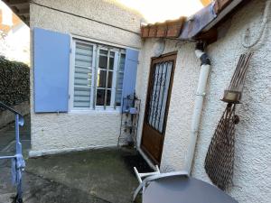 eine Tür eines Hauses mit einem Stuhl und einem Fenster in der Unterkunft Le Chalet in Saint-Germain-en-Laye