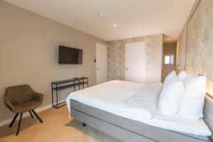 een slaapkamer met een groot bed en een stoel bij Residentie de Schelde - Apartments with hotel service and wellness in Cadzand-Bad