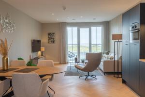 a living room with a table and chairs and a kitchen at Residentie de Schelde - Apartments with hotel service and wellness in Cadzand-Bad