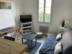 ein Wohnzimmer mit einem Sofa und einem TV in der Unterkunft Le Chalet in Saint-Germain-en-Laye