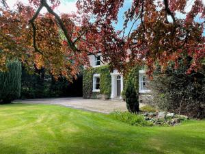 a house with a tree in front of a yard at 4 Bed-FreeWiFi-Sleeps 8-CarCharger in Kirmington