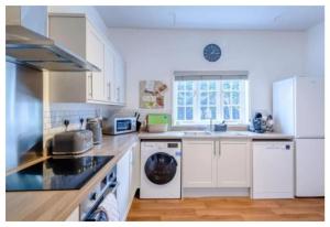 una cocina con armarios blancos y electrodomésticos blancos en Croxton House en Kirmington