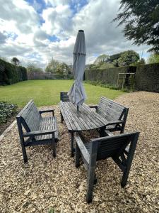 a picnic table with an umbrella and two chairs at Croxton House in Kirmington