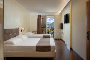 Hotel Savoy Palace - TonelliHotels في ريفا ديل غاردا: غرفه فندقيه بسرير وشرفه