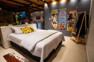- une chambre avec un lit et des affiches sur le mur dans l'établissement Cabana com Ofurô e Cinema a 6km do Centro, à Ibicaré