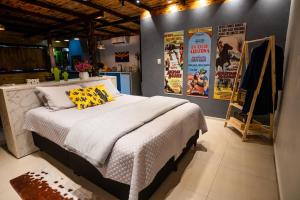 a bedroom with a bed and posters on the wall at Cabana com Ofurô e Cinema a 6km do Centro in Ibicaré