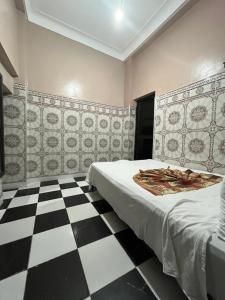 a bedroom with a bed and a checkered floor at Hotel Zagora in Marrakesh