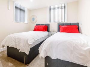 two beds in a bedroom with red pillows at 2 bed in Ellesmere 62544 in Ellesmere