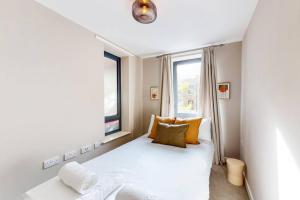 um pequeno quarto com uma cama branca e uma janela em Stunning 2 Bed Apartment with view of the Shard em Londres