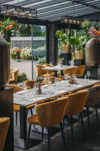 een lange tafel in een restaurant met stoelen en wijnglazen bij Hotel Schimmel in Woudenberg