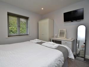 a bedroom with a white bed and a tv on the wall at 4 bed in Oswestry 73291 in Kinnerley