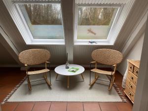 2 Stühle und ein Tisch in einem Zimmer mit 2 Fenstern in der Unterkunft Ferienwohnung An der Farchauer Mühle in Schmilau