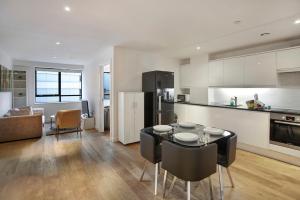 Lovely Spacious Central Croydon Apartment في كرويدون: مطبخ وغرفة معيشة مع طاولة وكراسي