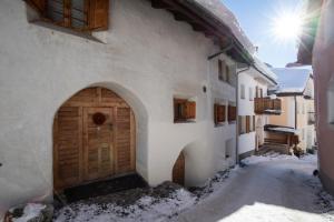 ein Gebäude mit einer Holztür im Schnee in der Unterkunft Chasa Curasch in Scuol