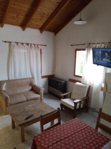 uma sala de estar com um sofá, uma mesa e uma televisão em Geraike em El Calafate