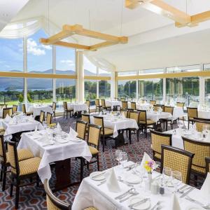 a restaurant with white tables and chairs and windows at Castlerosse Park Resort in Killarney