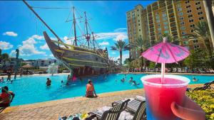 a person holding a drink with a pirate ship in a pool at Best Disney Resort Condo Orlando in Orlando