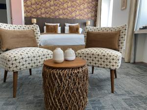 a bedroom with a bed and two chairs and a table at Cit'Hotel Hôtel de France et d'Europe in Concarneau