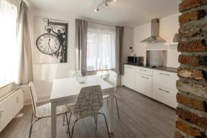 a kitchen with a table and chairs and a clock on the wall at Le Studio by La Reine City Center in Spa
