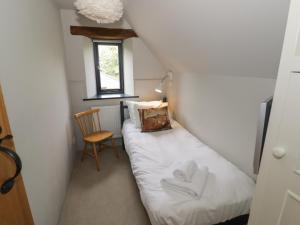 ein kleines Zimmer mit einem Bett und einem Stuhl in der Unterkunft The Cottage in Chipping Campden