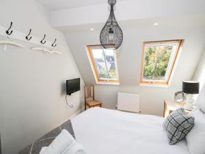 1 dormitorio con 1 cama blanca y 2 ventanas en The Old Stables en Chipping Campden