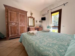 Hotel I Menhirs في Annunziata: غرفة نوم بسرير وبطانية خضراء ومرآة
