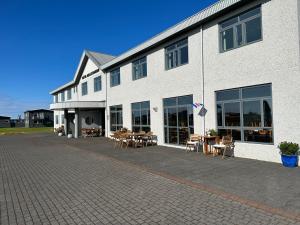 海德利桑德Adventure Hotel Hellissandur的一座白色建筑，前面摆着桌椅