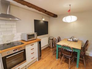 a kitchen with a table with a microwave and a table with chairs at The Old Brewhouse in Chipping Campden