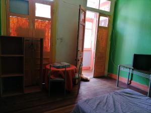 um quarto com uma mesa e um quarto com paredes verdes em Hostal del gato em Valparaíso