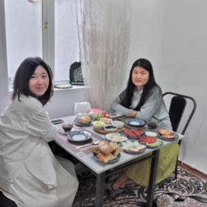 two women sitting at a table with food on it at Гостевой дом "BAXSHILLO" in Bukhara