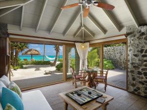 a living room with a table and a view of the ocean at Petit St. Vincent Resort in Petite Martinique