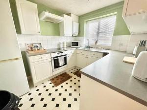 a kitchen with white cabinets and a checkered floor at Enjoy The Willow, lovely home to stay & relax while in Ashford! in Ashford