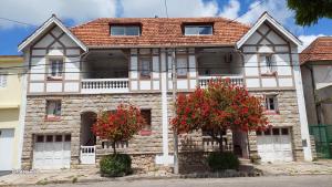 una vecchia casa con fiori rossi davanti di Hostería Almirante Brown a Mar del Plata