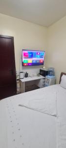 a bedroom with a bed and a desk with a computer monitor at JVcribstudios-Ndemi gardens apartments in Nairobi