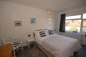 a bedroom with a bed and a chair and a window at Berry Cottage in Sheringham