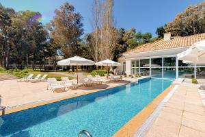 - une piscine avec des chaises et des parasols à côté d'une maison dans l'établissement Oceana Suites en Green Park, playa Solanas, à Punta del Este